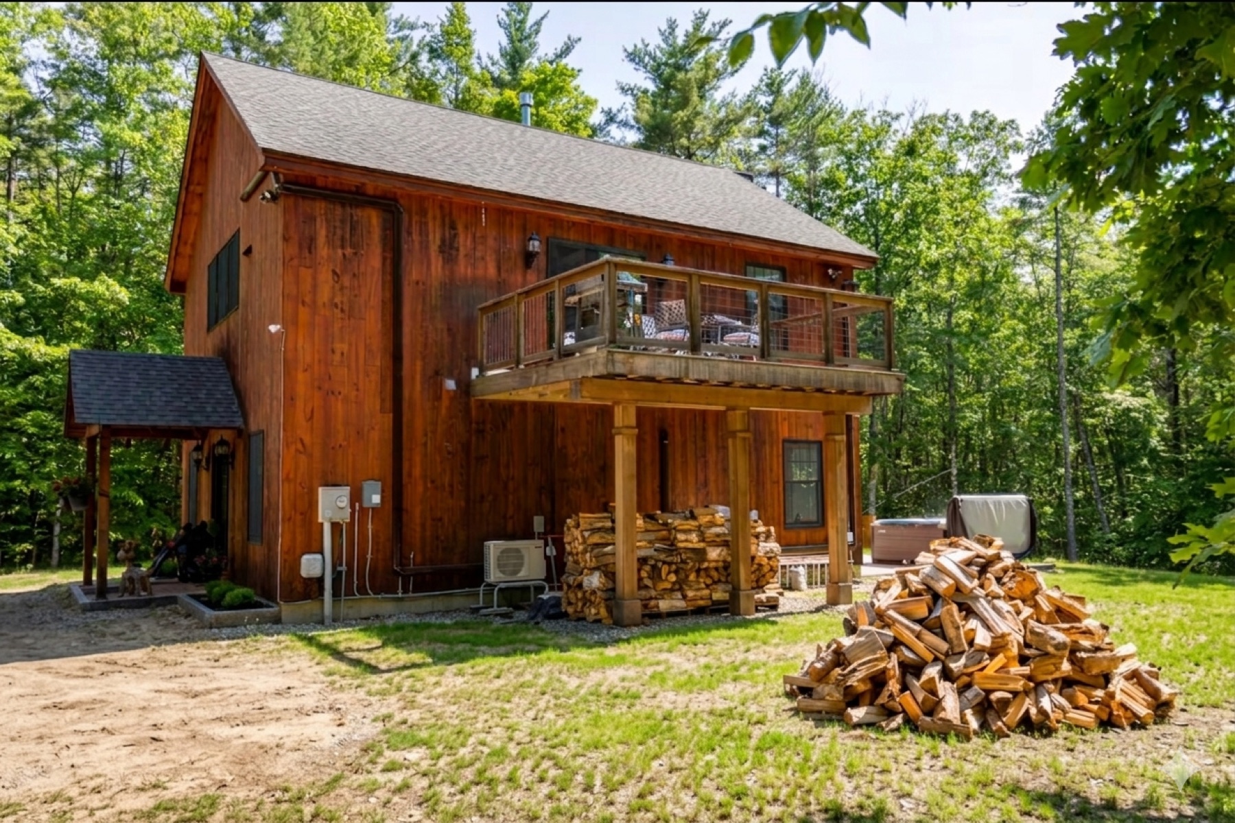 Side view of the home with an elevated covered deck and a generous stack of firewood beside it